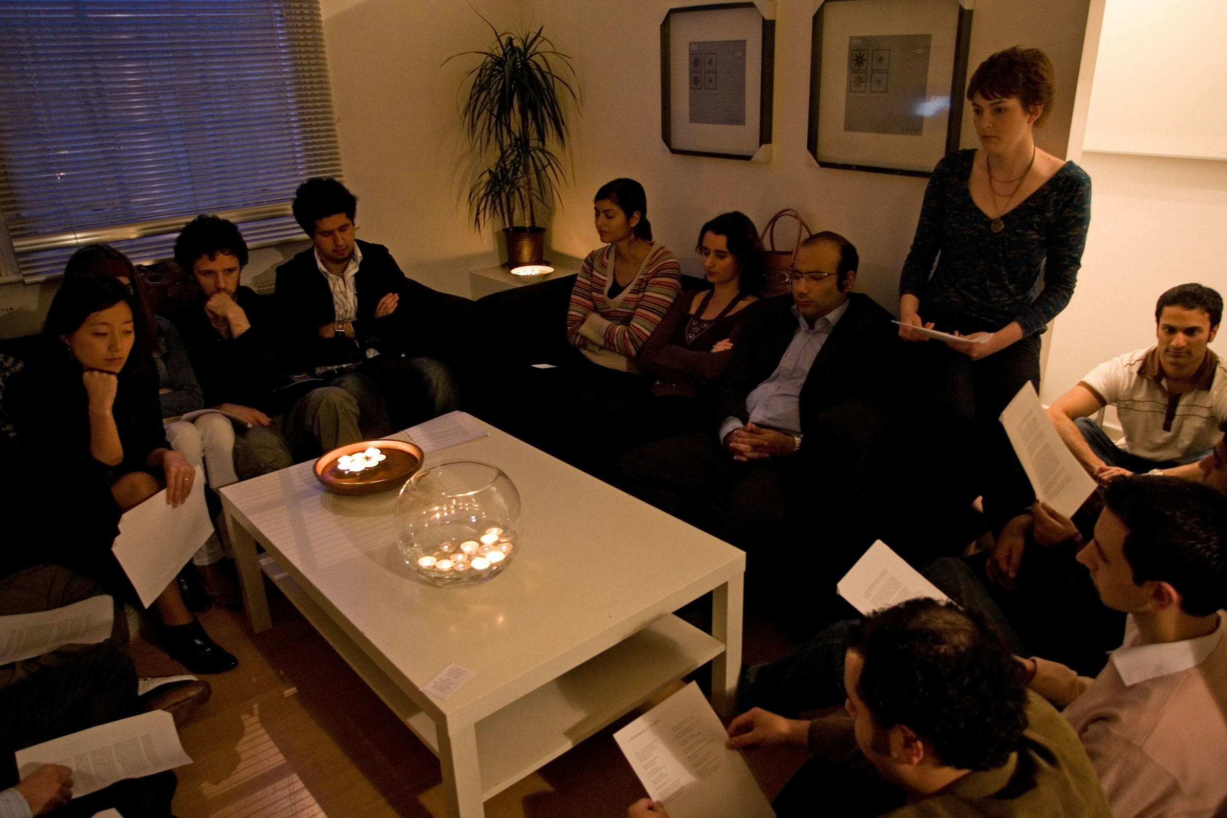 A devotional gathering of friends sharing prayers and readings in a living room.